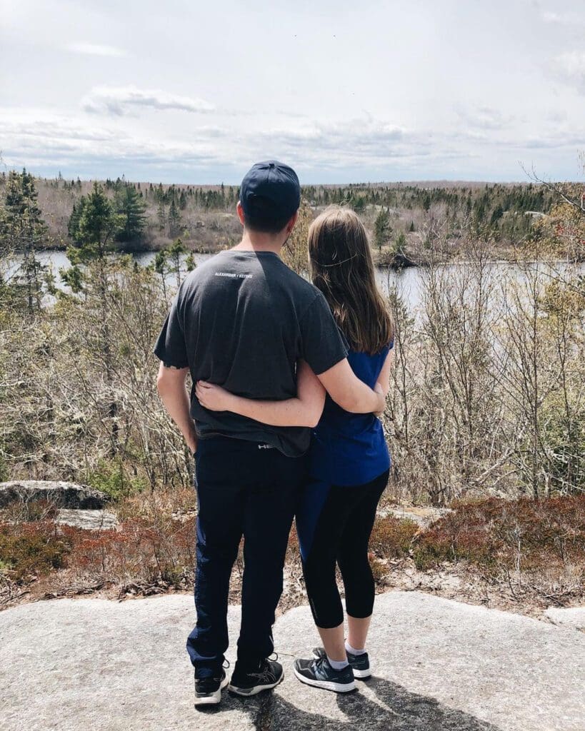 A couple in an embrace overlooking a lakeside view at a Halifax hiking spot.