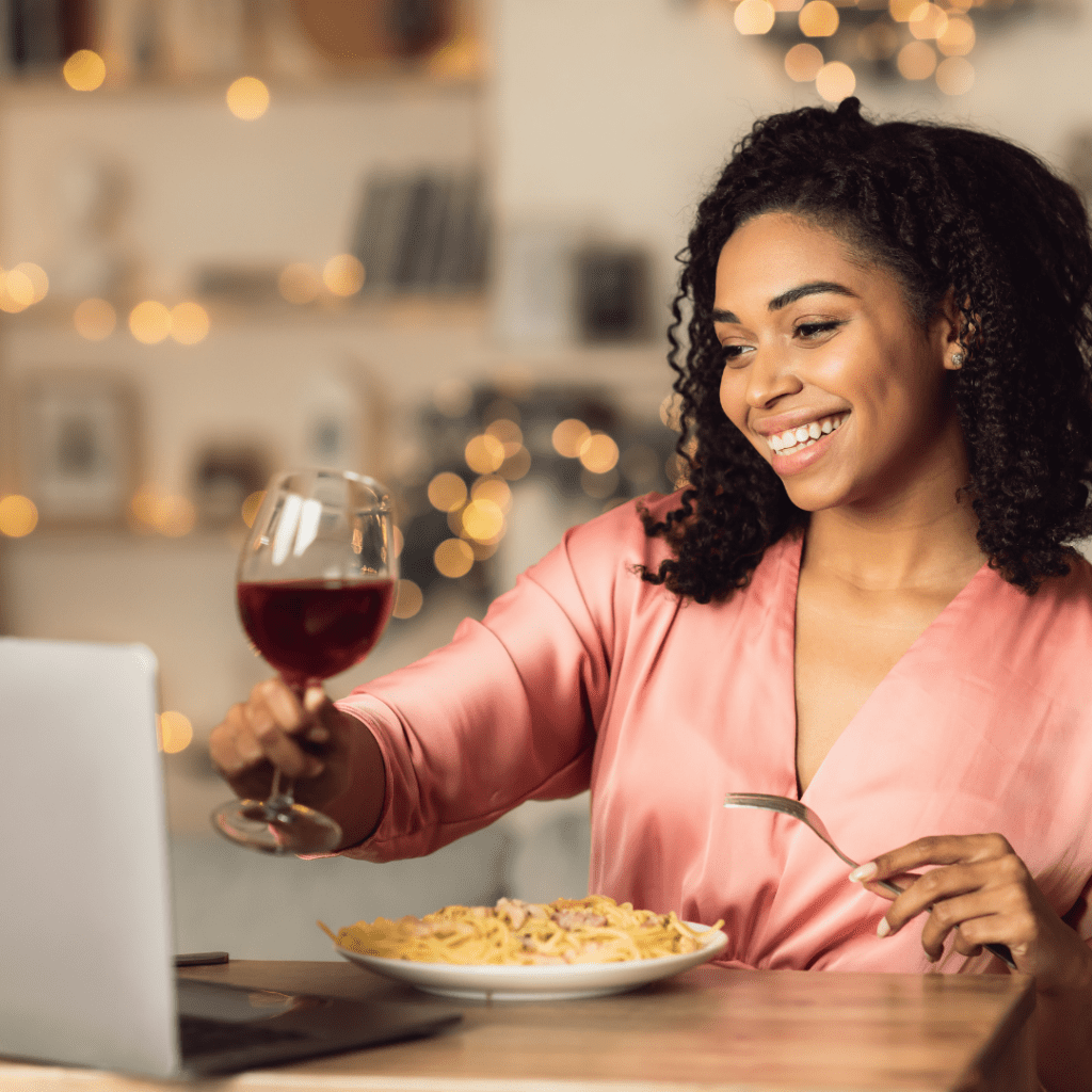 Woman smiling while having dinner during one of her virtual first dates. 