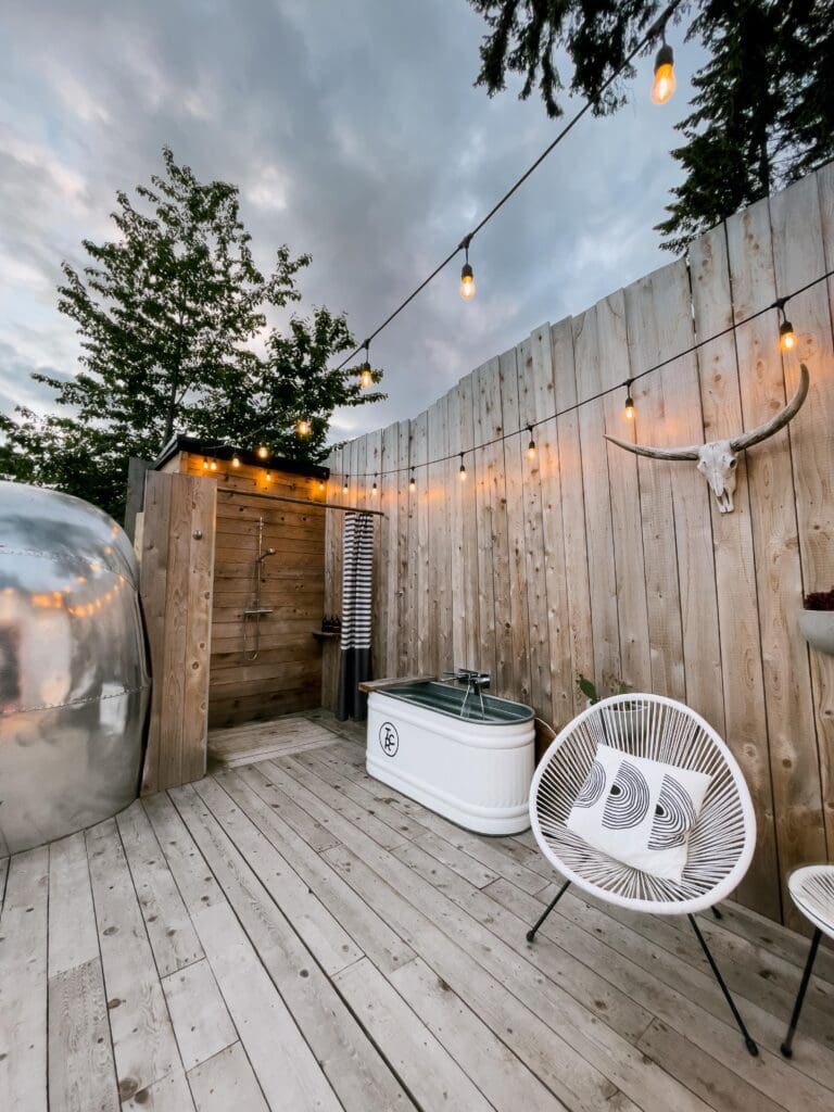 A view of the outdoor shower, metal bathtub, and seating area next to the airstream at Tin Can Ranch