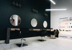 inside of a hair salon, chairs lined up in a row infront of mirrors