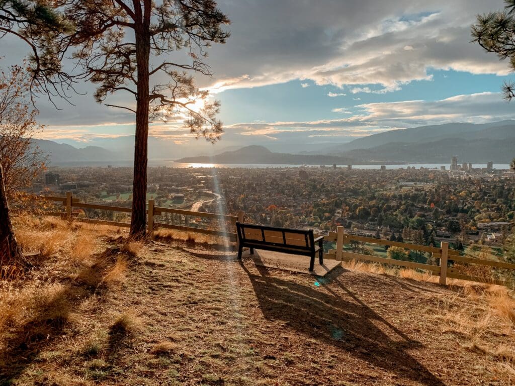 A park bench overlooking Kelowna. The sky is blue and the clouds are rolling in.