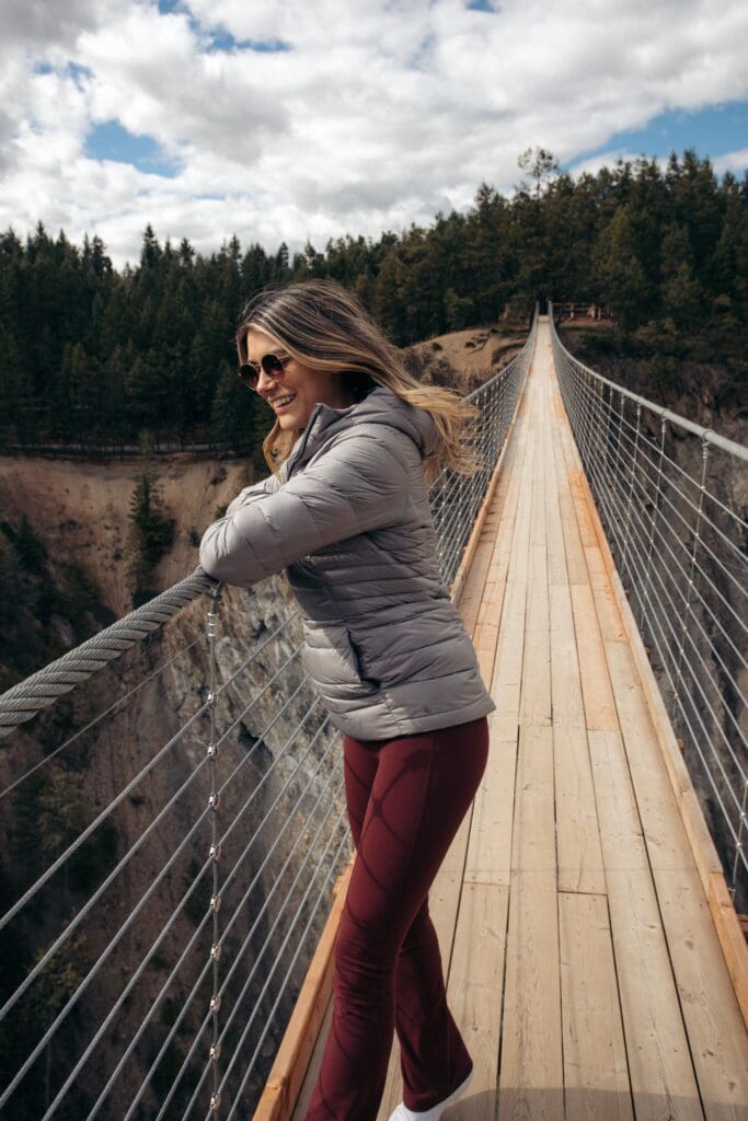 A girl standing on the golden sky bridge in the sun over looking the 426 foot canyon below