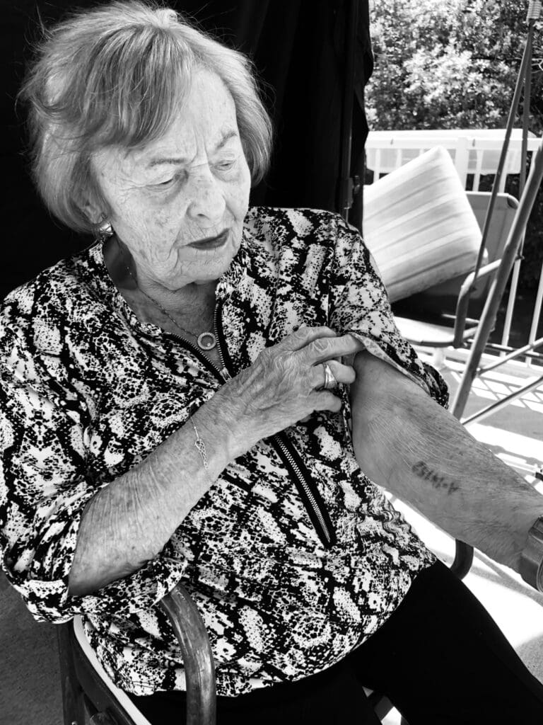 elderly woman holocaust survivor showing her arm tattoo