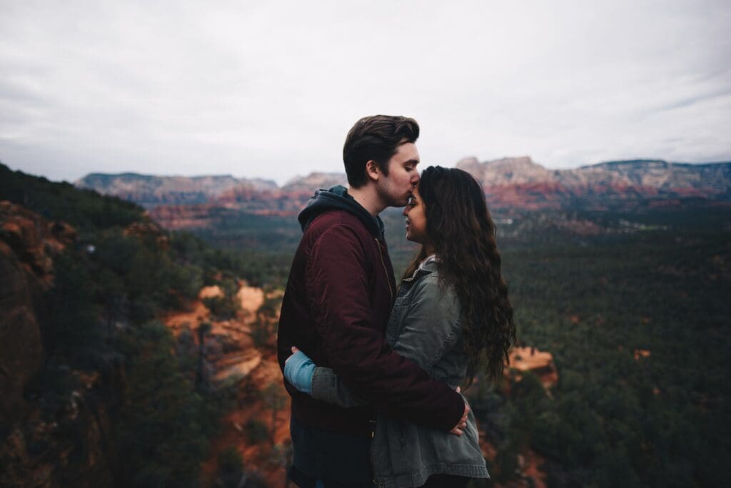 Couple in an embrace with a scenic fall background.