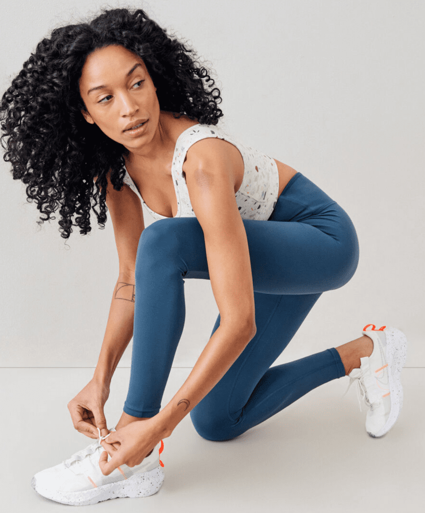 Woman tying her shoelaces and wearing the Roots Terazzo Crop Tank.