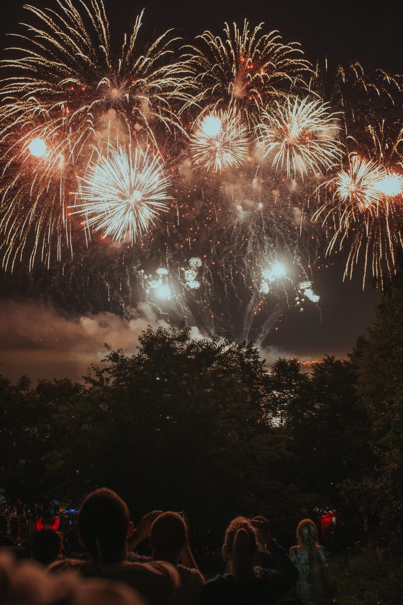 Crowd of people watching beautiful fireworks at a festival.