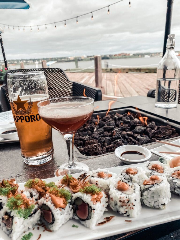 A delicious plate of sushi served on a fire table with a breathtaking water view.