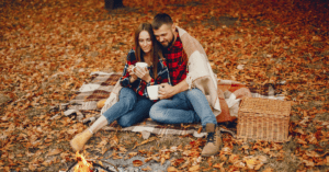A couple enjoying a picnic date surrounded by leaves and spectacular fall views.