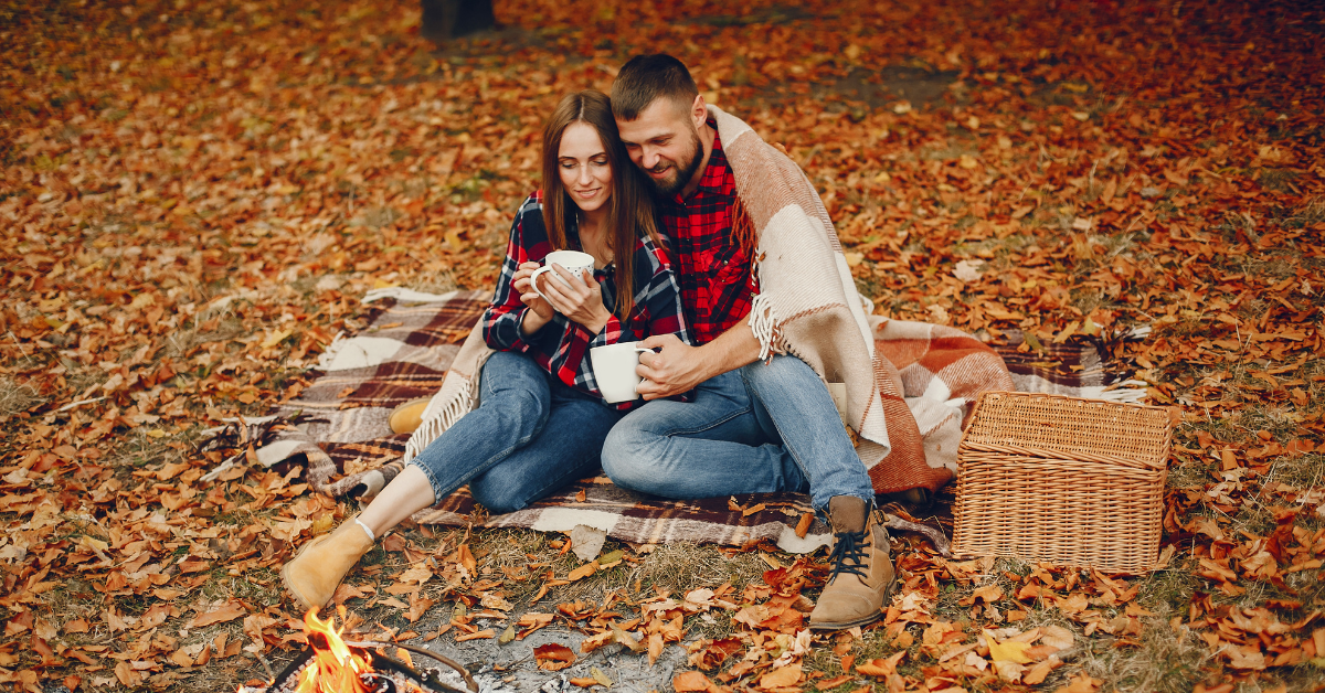 A couple enjoying a picnic date surrounded by leaves and spectacular fall views.