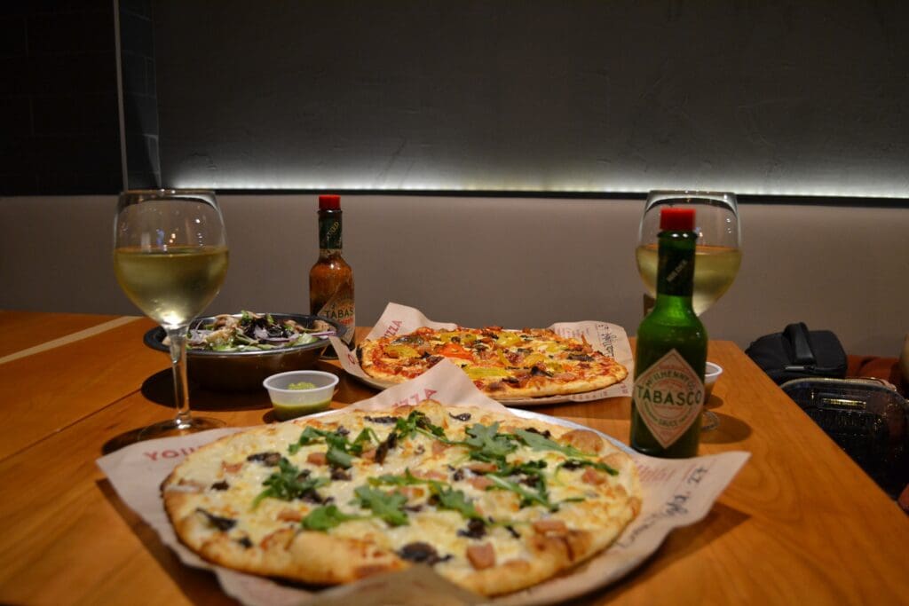 Score Pizza served with glasses of wine.