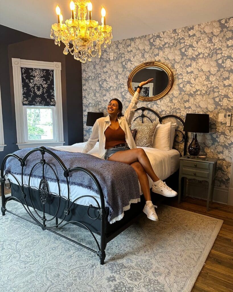 A girl setting on the bed of the beautiful Slaymaker & Nichols Mlle Caroline suite.