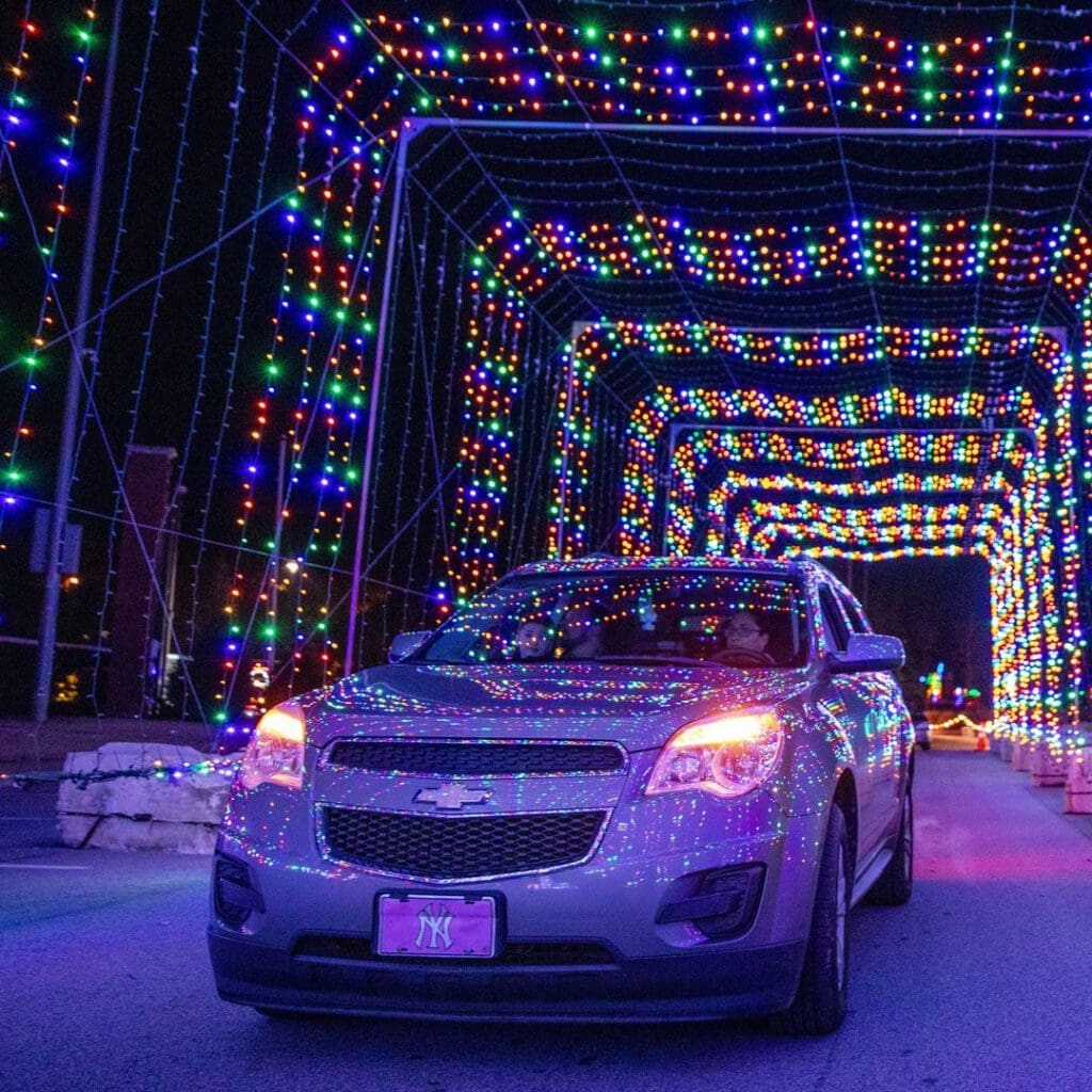 A car driving through a tunnel of holiday lights at the Magic of Lights event in Ottawa.