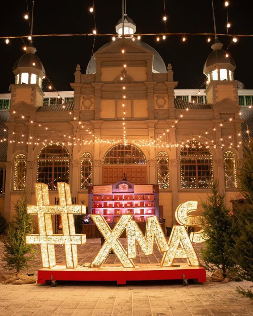 A photograph of a #XMAS sign in front of the Aberdeen Pavilion building at the Ottawa Christmas Market.