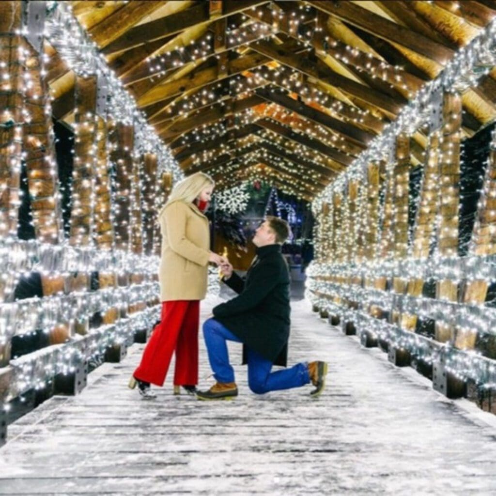 A romantic proposal under a tunnel of sparkling lights at the Magic of Lights event.