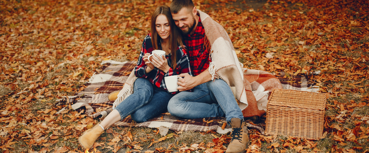 A couple enjoying a picnic date surrounded by leaves and spectacular fall views.