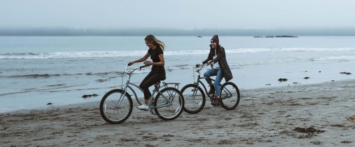 Two girls riding bikes on MacKenzie Beach in Tofino BC