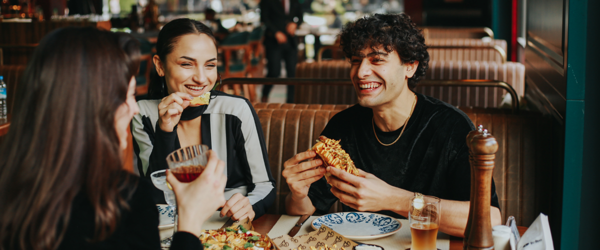 a group of friends sitting down at a restaurant eating food