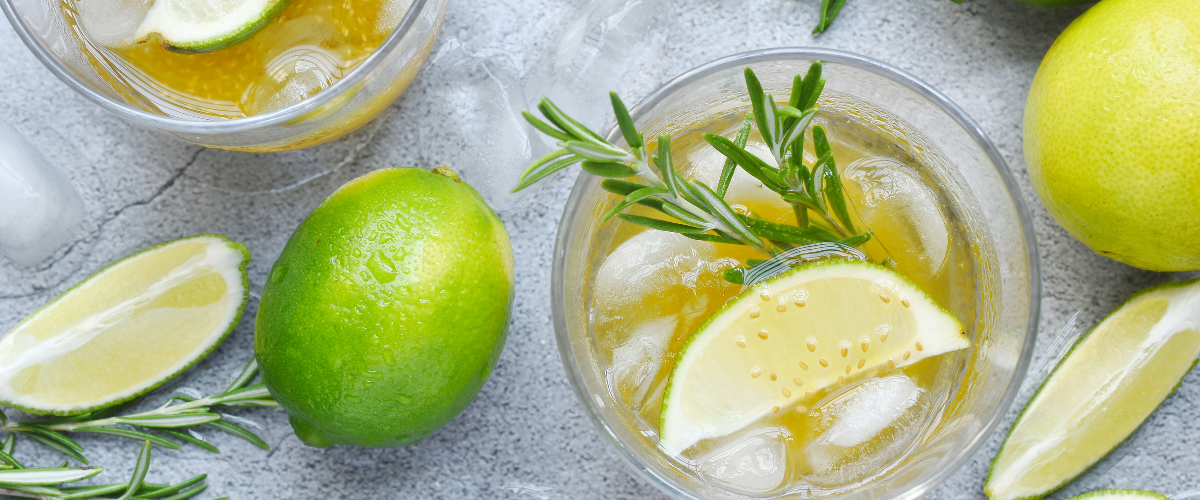 limes laying around a glass filled with lime drink
