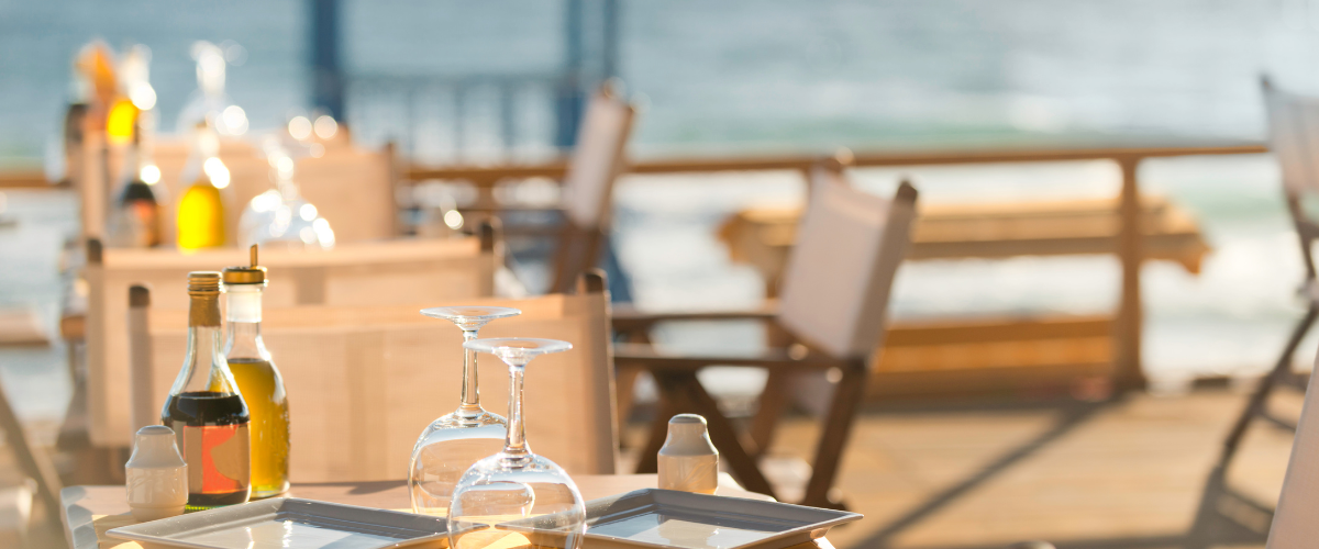 Dining table set with a beautiful view of the water in the background.