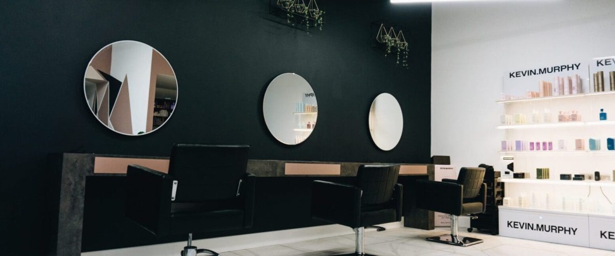 inside of a hair salon, chairs lined up in a row infront of mirrors